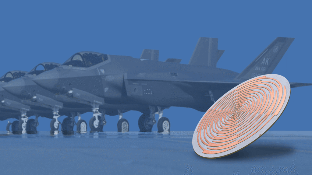 Photo-etched circular copper component beside F-35 fighter jets